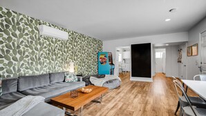 A modern living room with a grey sofa, a wooden coffee table, and a patterned wall. - EXCLUSIVE *PRIVATE* COMPOUND~ The Three Ten Hotel (Palm Springs)