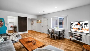 A modern living room with a dining area, a kitchen, and a TV displaying 'The Thretten Hotel Palm Springs'. - EXCLUSIVE *PRIVATE* COMPOUND~ The Three Ten Hotel (Palm Springs)