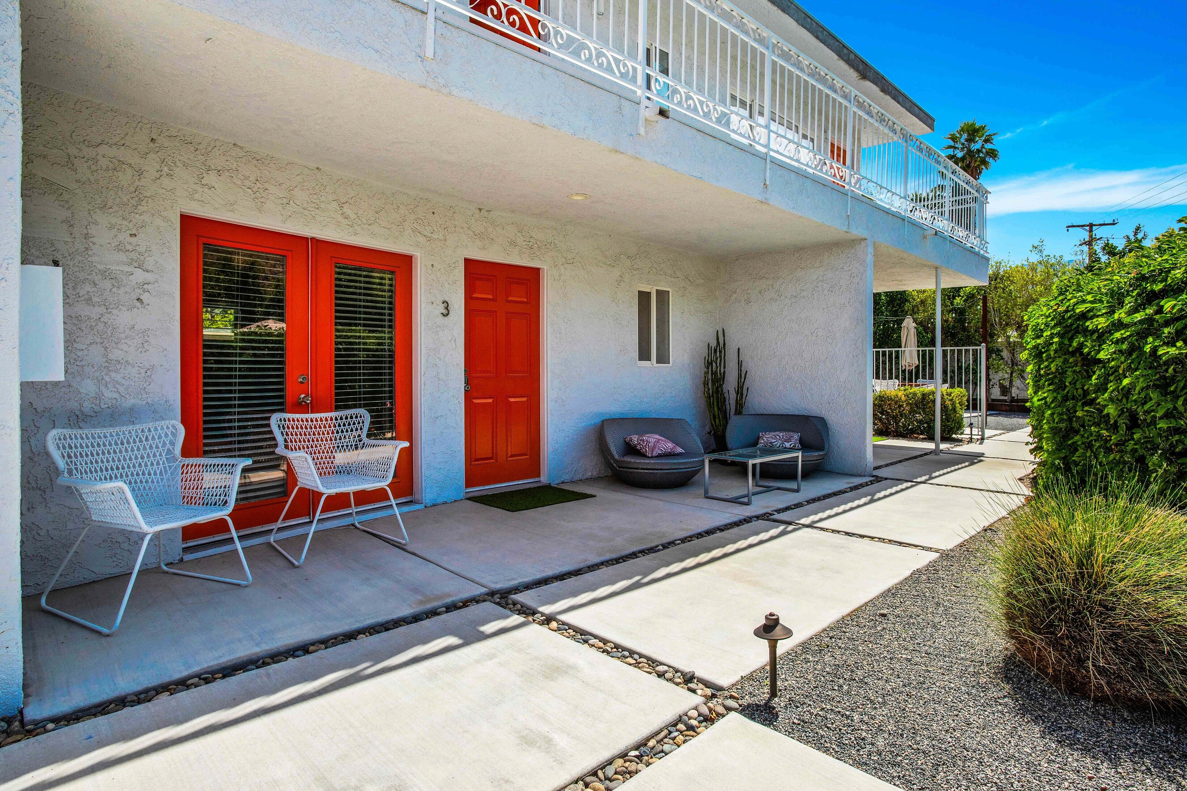 A two-story building with a balcony, red doors, and outdoor seating.