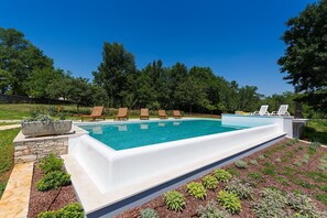 Et rektangulært swimmingpool med en stenbord og en stenskulptur på den ene side.