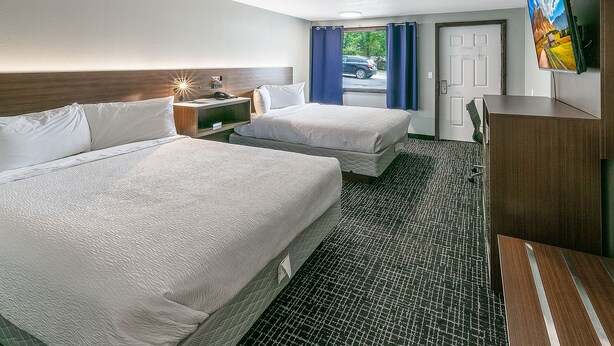Habitación de hotel con dos camas, un escritorio, televisión y vistas al exterior.