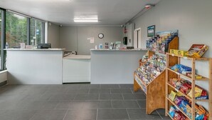 Zona de recepción con mostrador, reloj y exhibidor de revistas.