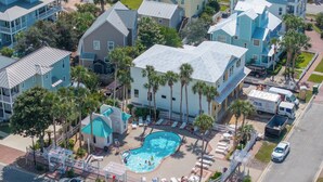 An aerial view of a resort with a central swimming pool, multiple buildings, and a parking area. - Pet-Friendly | Steps to Beach | Pool (Destin)