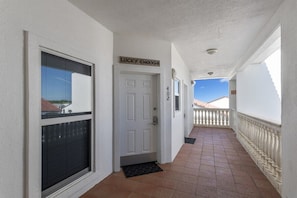 A corridor with a white door, a sign above it, and a balcony with a railing. - Grand Playa, Unit 402 | Gulf - Front Condo | Priva (Santa Rosa Beach)