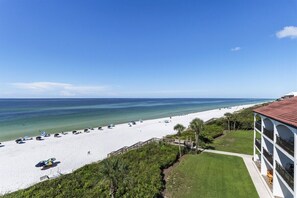 Una spiaggia con sabbia bianca, ombrelloni e un cielo azzurro limpido.