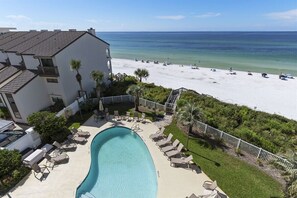 A pool area with lounge chairs and a view of the beach.