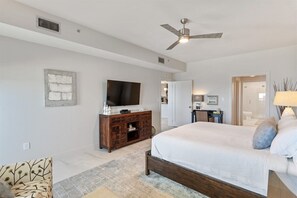 A spacious bedroom with a large bed, a television, a ceiling fan, and a wooden cabinet. - Grand Playa, Unit 402 | Gulf - Front Condo | Priva (Santa Rosa Beach)