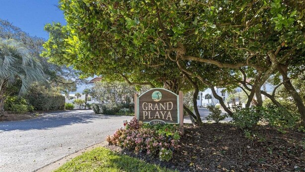A sign for 'Grand Playa' with a view of a road and surrounding greenery. - Grand Playa, Unit 402 | Gulf - Front Condo | Priva (Santa Rosa Beach)