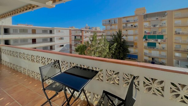 Ein Balkon mit Tisch und Stühlen, mit Blick auf ein Wohngebiet mit mehrstöckigen Gebäuden.