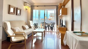 A compact living space with a sofa, chairs, a small table, and a balcony with a view. - TERRASOL PLAZAMAR 2-6 (Torre del Mar)