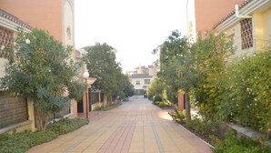 Un sendero pavimentado bordeado por edificios y vegetación, que conduce a una estructura distante.