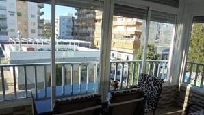 Ein Balkon mit Tisch und Stühlen mit Blick auf eine Stadtlandschaft mit Gebäuden und parkenden Autos.