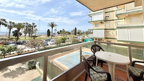 Ein Balkon mit Blick auf einen Pool, Palmen und einen Strand.