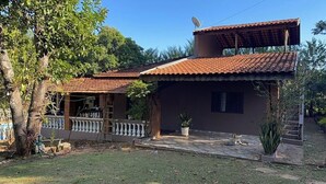 A two-story house with a tiled roof, a balcony with a railing, and a satellite dish. - Chacara Zabotto (São Carlos)
