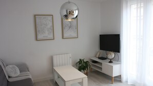A modern living room with a white sofa, a white table, a globe, and a TV on a white cabinet. - Edificio Privado La Herradura (Haro)
