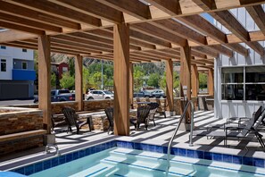 A covered outdoor pool area with wooden beams, stone steps, and lounge chairs. - Fairfield Inn & Suites by Marriott Hailey Sun Valley (Hailey)