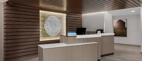Una moderna recepción con un muro de listones de madera, una pantalla digital y una obra de arte enmarcada.