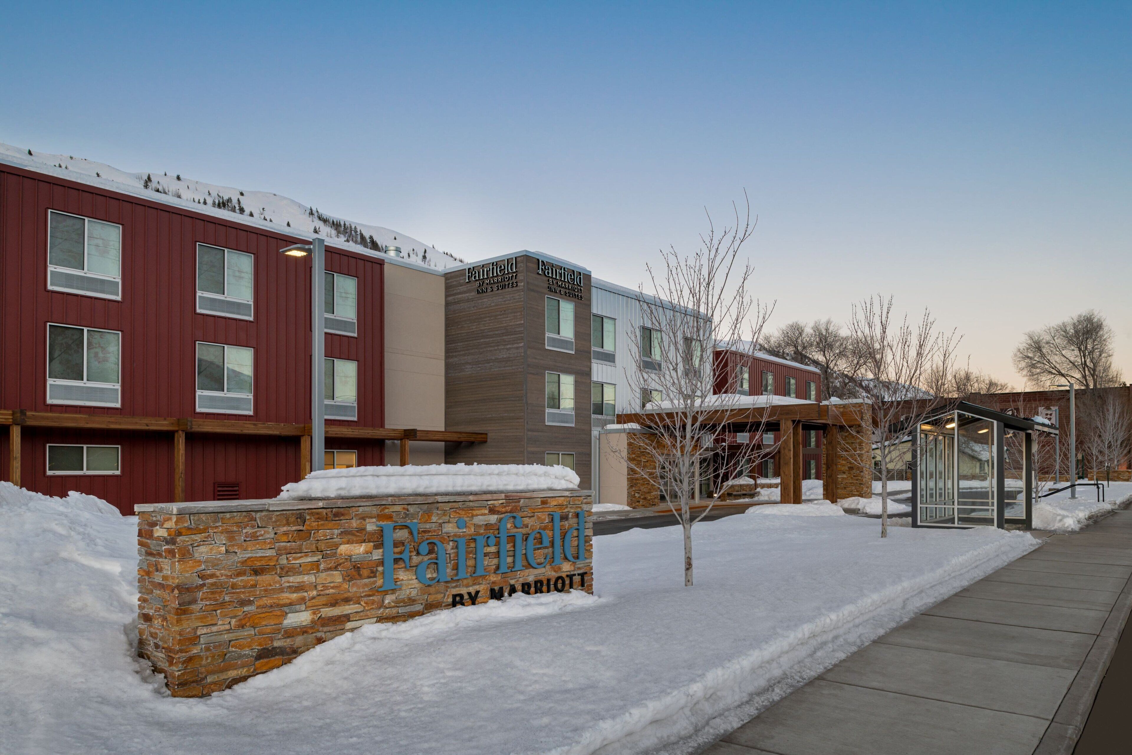 A Fairfield by Marriott hotel with a stone facade, multiple windows, and a snow-covered ground.