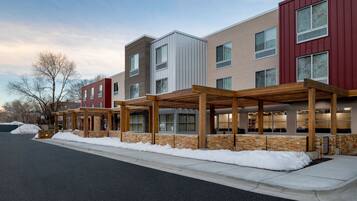A multi-story building with a covered outdoor area and snow on the ground.