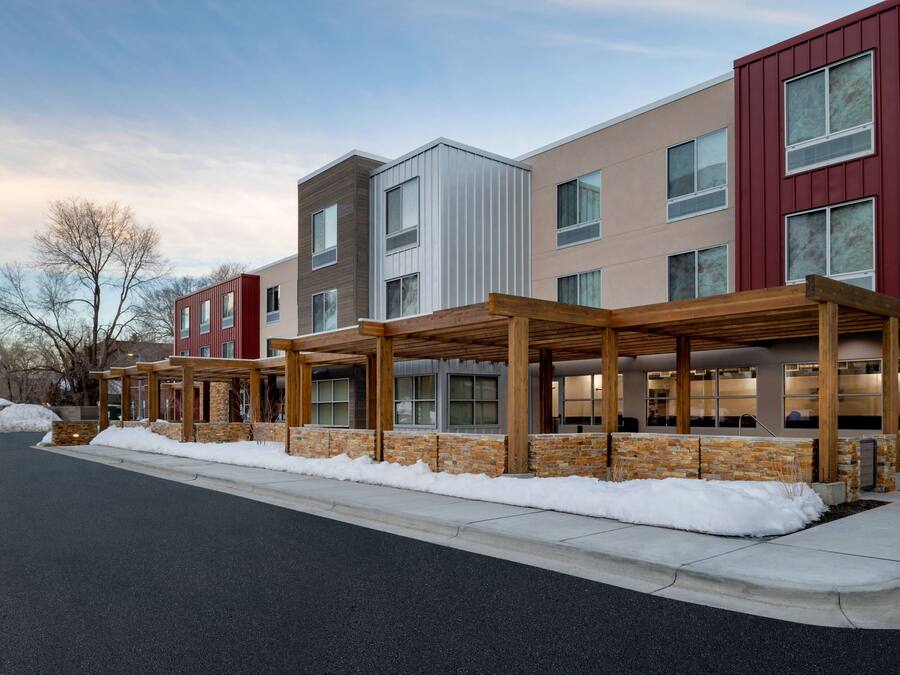 A multi-story building with a covered outdoor area and snow on the ground.