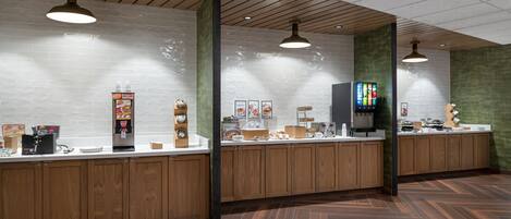 Un espace cuisine moderne avec des meubles en bois, un plan de travail blanc et un sol Ă motifs en chevrons.