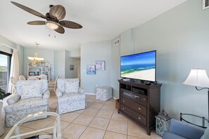 Una sala de estar con ventilador de techo, televisor y muebles con diseño.