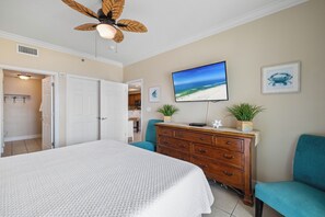 A bedroom with a bed, a dresser, a television, and a ceiling fan.