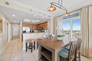 A spacious kitchen with wooden cabinets, a stainless steel refrigerator, and a dining area with a wooden table and chairs.