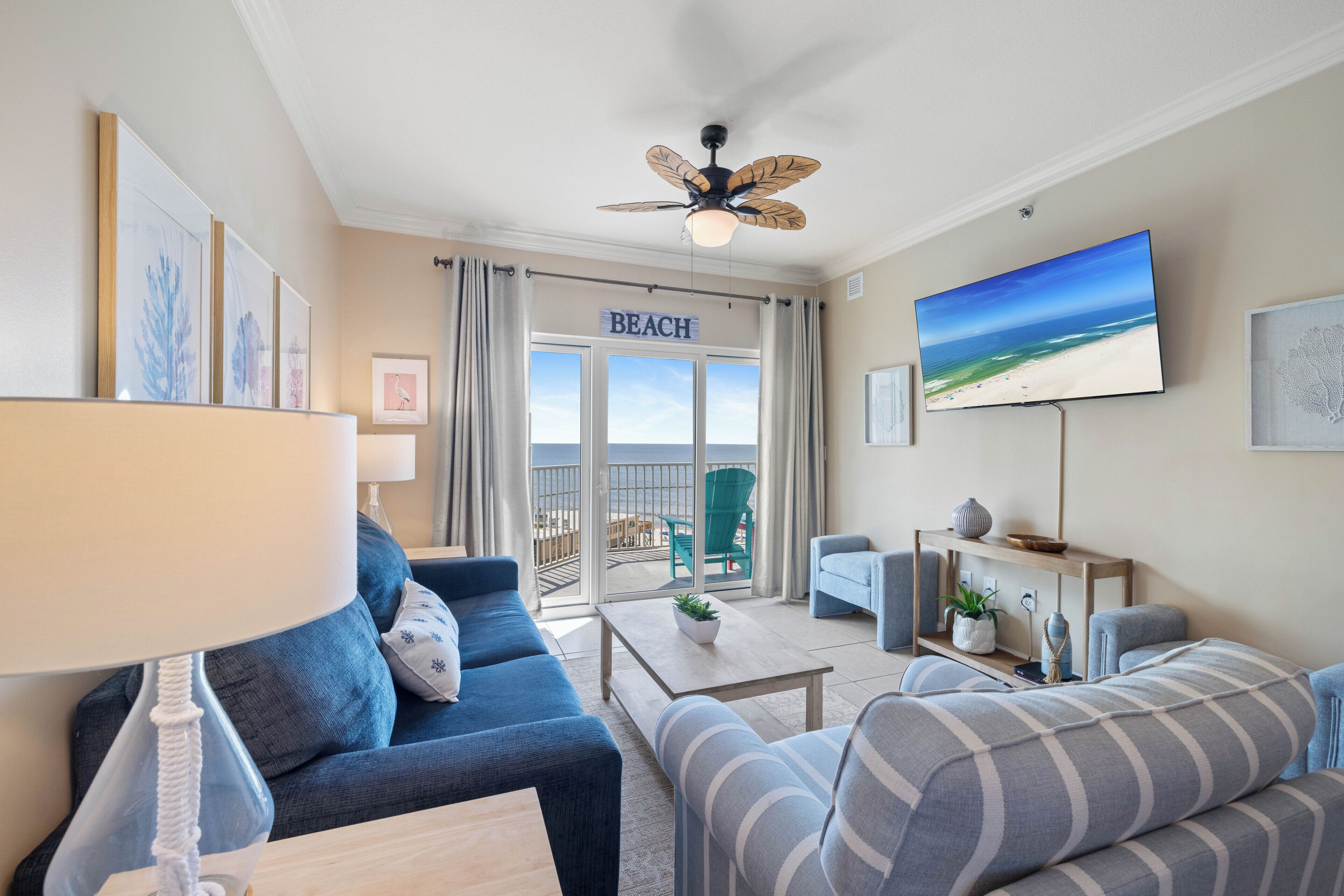 Una sala de estar con sofá, mesa de centro, televisor y balcón con vista a la playa.
