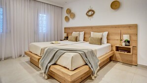 Een moderne slaapkamer met een houten hoofdbord, twee bedden, een nachtkastje en een bijzettafeltje.