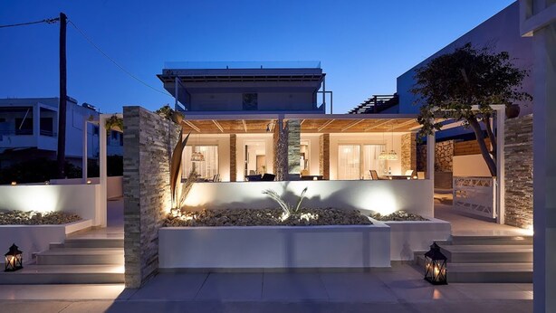 Een modern huis met een ruim terras, stenen muren en een goed verlichte ingang.