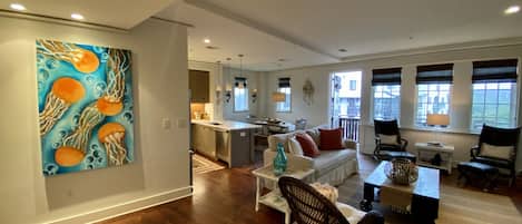 A spacious living area with hardwood flooring, a kitchen with a central island, and a dining area with a table and chairs.