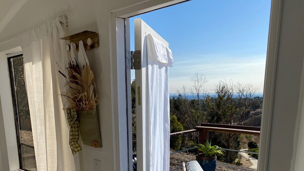 A room with a sliding glass door leading to an outdoor deck with lounge chairs and a potted plant.