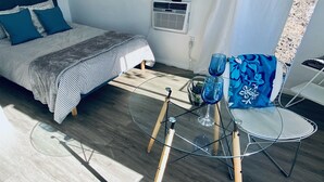 A modern bedroom with a bed, a small table with chairs, and a window with curtains.