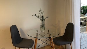 Een eethoek met een glazen tafel en twee stoelen, een vaas met bloemen, en een bord met daarop 'BEACH'.