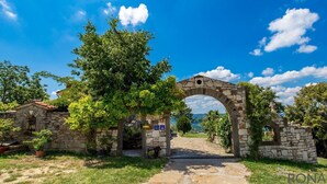 A stone archway leading to a rustic building with a sign indicating a historical site.