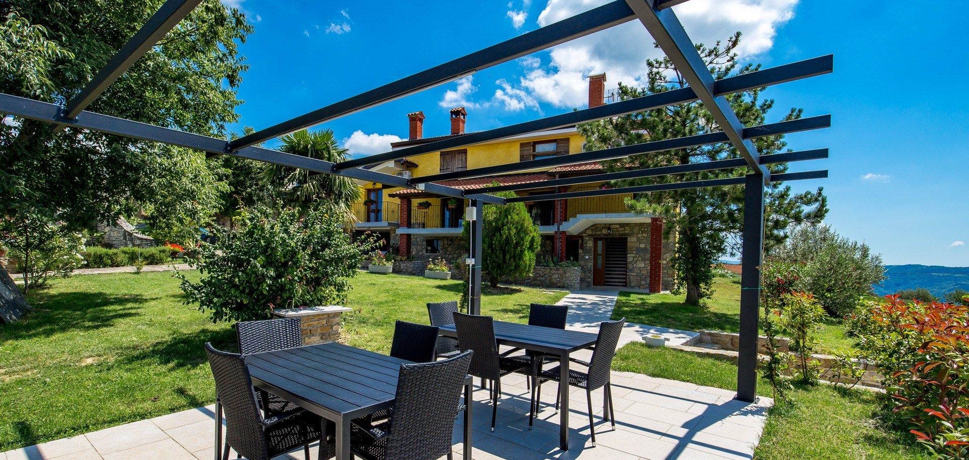 Une terrasse extérieure dotée d’une pergola, d’une table à manger et de chaises.