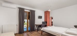 Ein Schlafzimmer mit einem Bett, einem Schreibtisch, einem Fernseher und einem Kamin aus Ziegelsteinen.