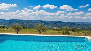 Ein klares, blaues Schwimmbecken mit Blick auf Berge und Bäume im Hintergrund.