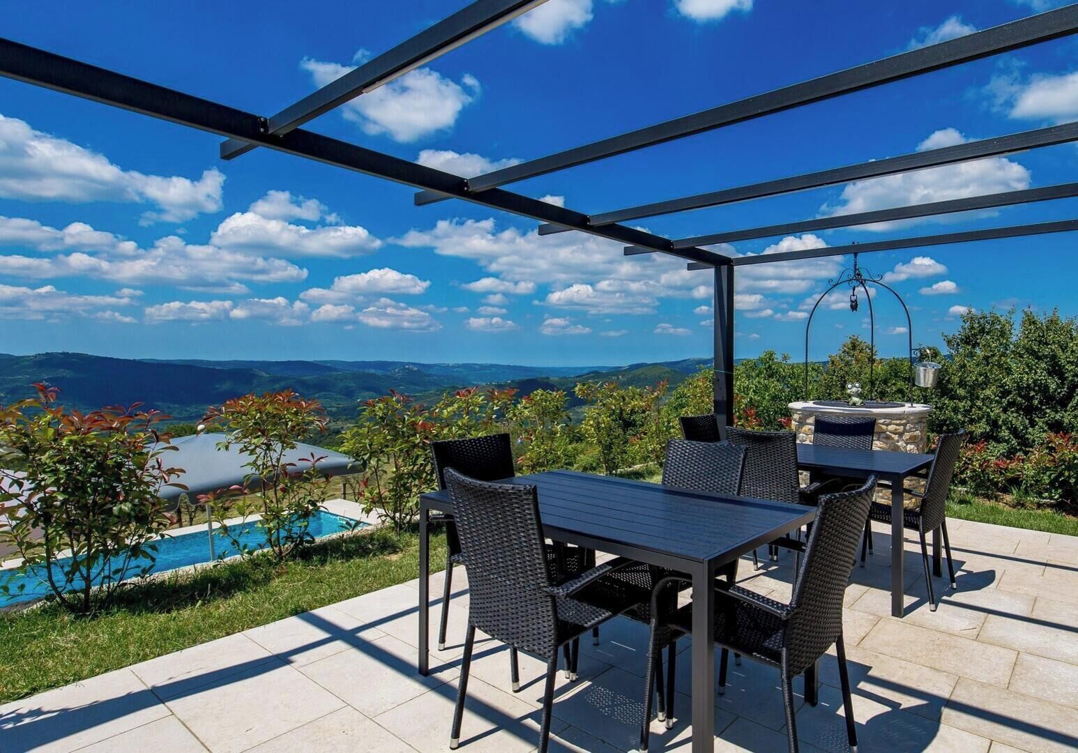 An outdoor patio with a table and chairs, a pool, and a view of the landscape.