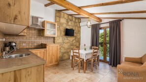 Kitchen area with stove, sink, and dining space, featuring a simple table and four chairs.