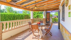 Eine Außenpatio mit Tisch und Stühlen, einer Pergola und Blick auf Grünflächen und Berge.