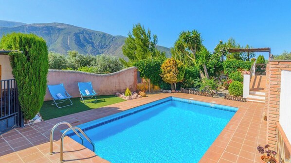 A swimming pool with two lounge chairs, a pergola, and a mountain view. - Cortijo El Olivar Órgiva by Ruralidays (Granada)