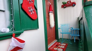 A front door with a red doorbell, a Christmas ornament, and a blue chair outside. - Alpine •air•B&B- A Charming •air•B&B in Downtown Helen, GA! (Helen)
