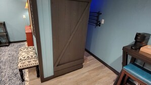 A room with a wooden floor, a blue wall, a bench, a small table, and a door. - Alpine •air•B&B- A Charming •air•B&B in Downtown Helen, GA! (Helen)