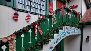 A staircase with Christmas decorations, a sign for a Georgia Wine Tasting Room, and potted plants at the bottom. - Alpine •air•B&B- A Charming •air•B&B in Downtown Helen, GA! (Helen)