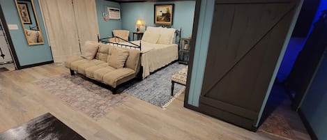 A bedroom with a bed, a sofa, a small table, and a mirror.