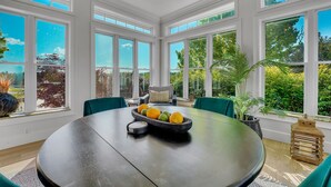 A dining area with a round table, a bowl of fruit, and a view of the outdoors through large windows. - 6BR/4.5BR Retreat: Views, Pool, HotTub, Sauna & Game-room (Leicester)