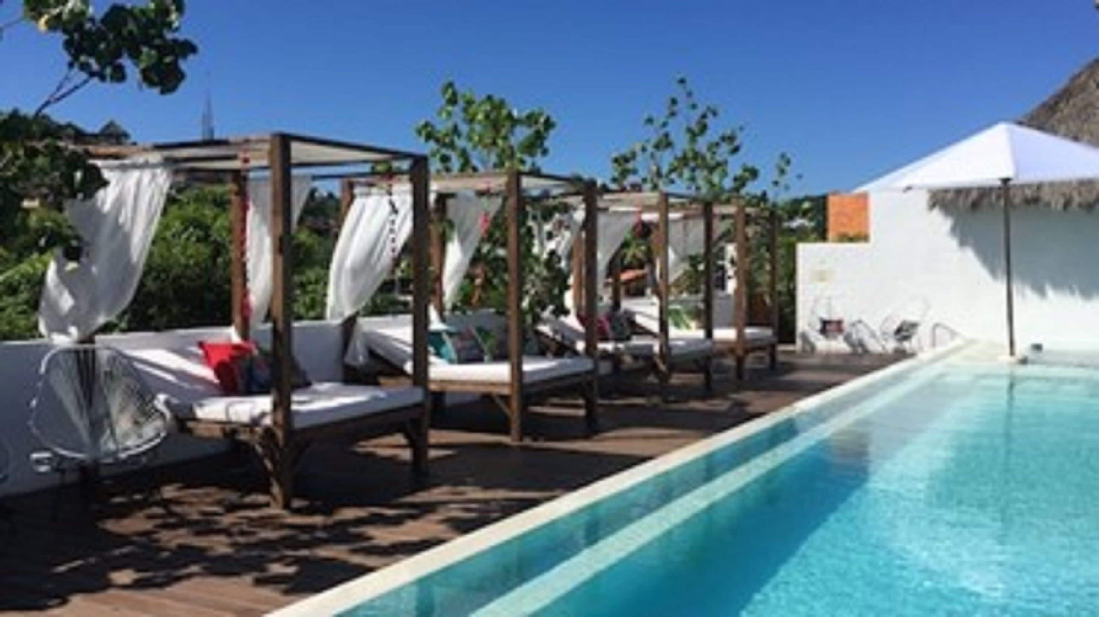 A poolside area with sunbeds and a canopy structure.