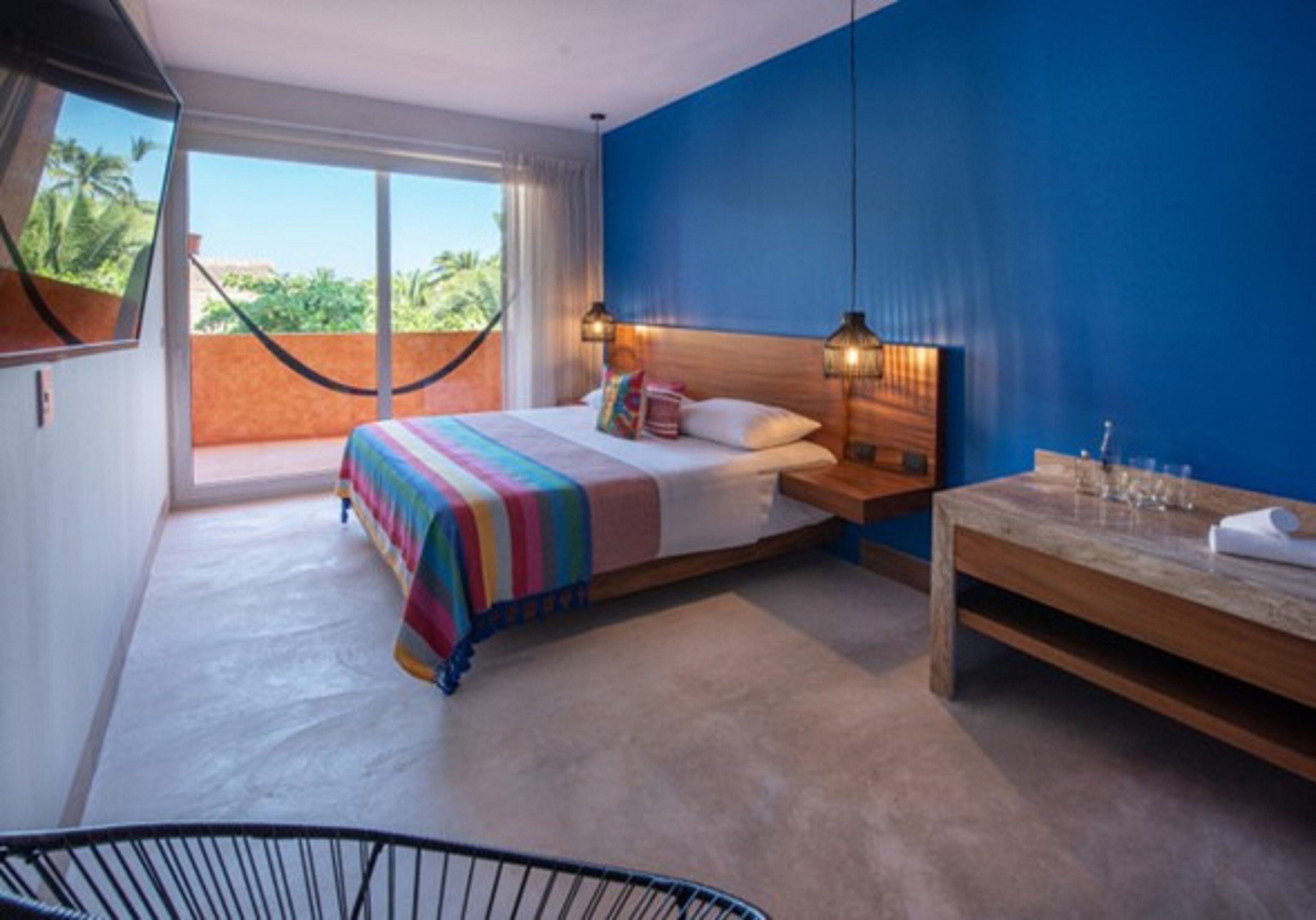 A bedroom with a bed, bedside table, and a view of the outdoors.
